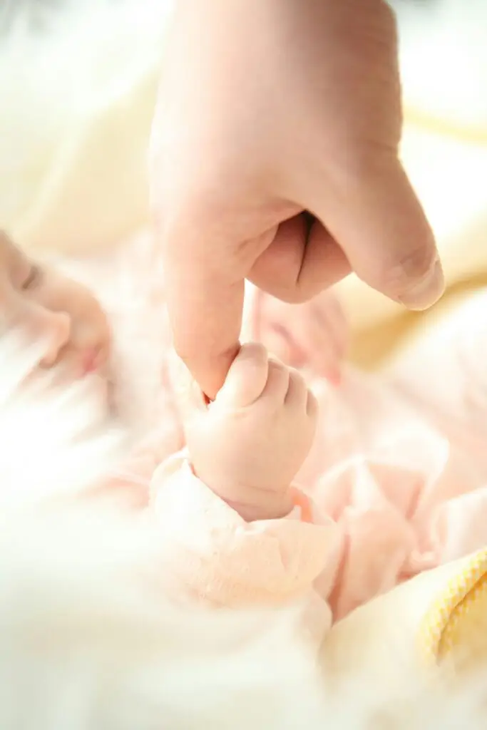 newborn asleep holding adults hand